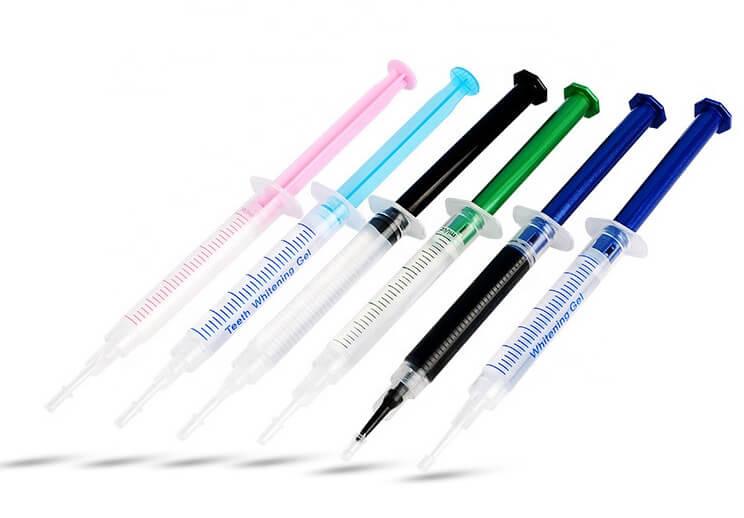 Assorted syringes of LaserGlow hydrogen peroxide teeth whitening gel in various colors, used for professional and at-home whitening treatments