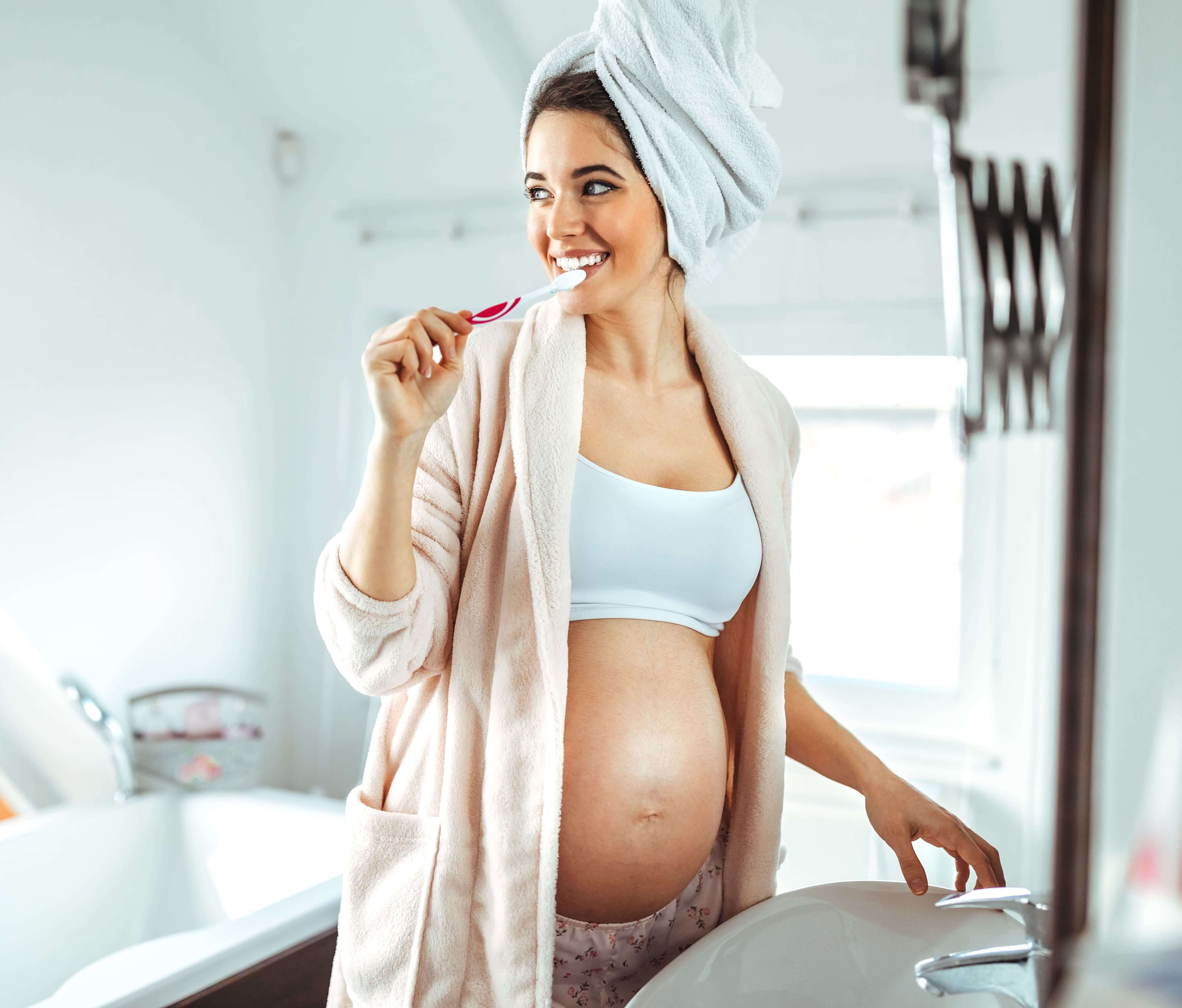 Pregnant woman brushing her teeth with LaserGlow Purple Toothpaste—a peroxide-free, ADA-recommended option for safe whitening during pregnancy
