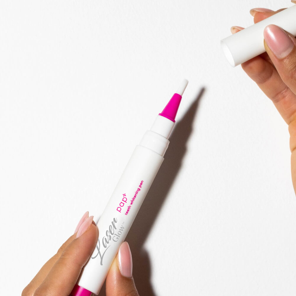 Close-up of a hand twisting the bottom of the Laserglow PAP+ teeth whitening pen to dispense.
