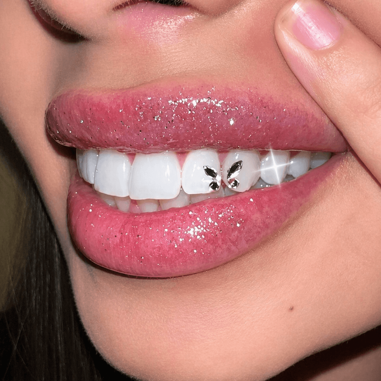 Close-up of crystal butterfly tooth gem on front teeth.