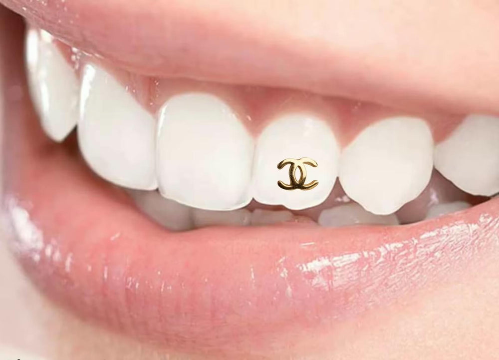 Macro view of a gold-plated Chanel-style interlocking-C tooth gem sparkling on an incisor.