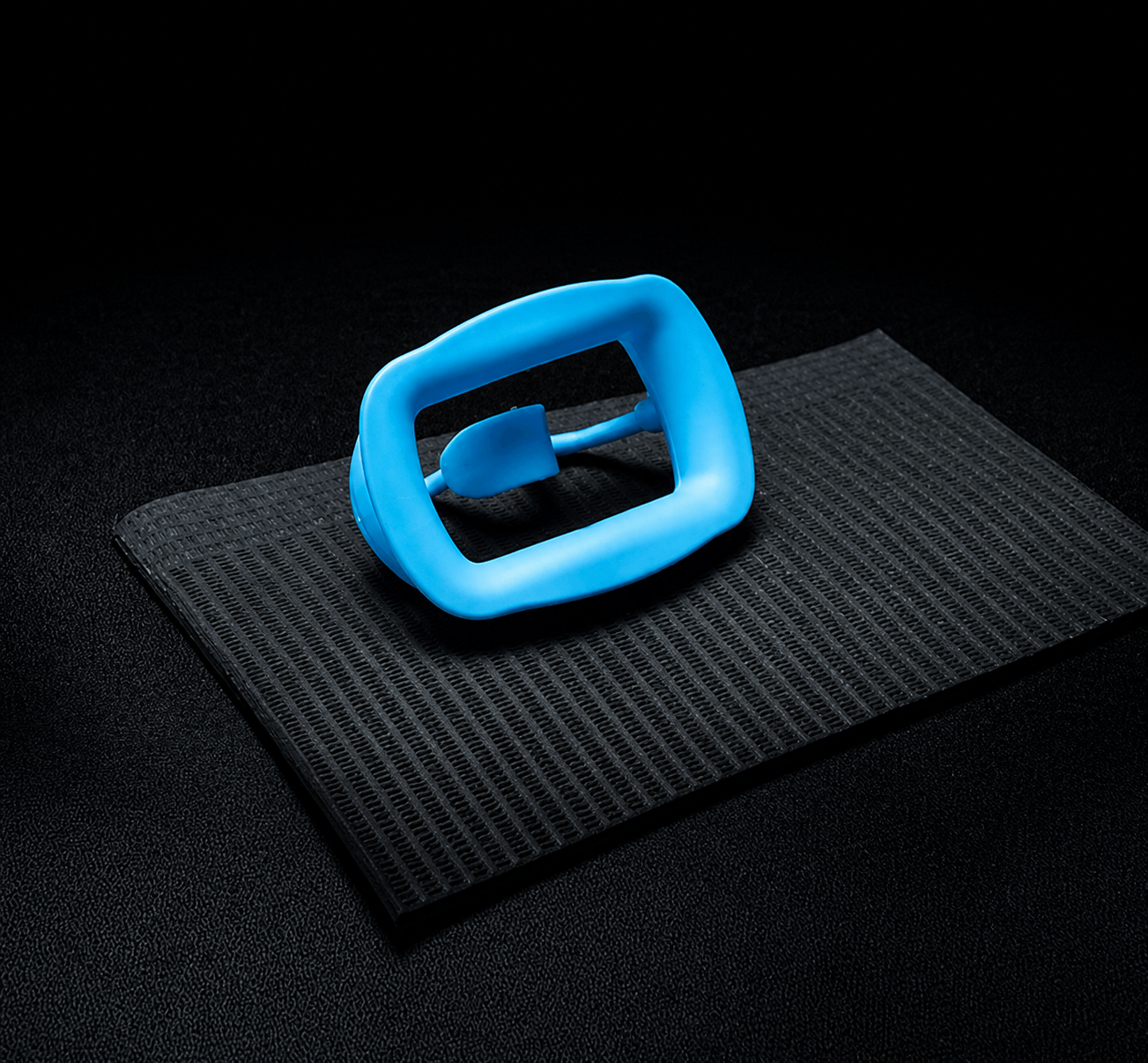 Black 3-ply waterproof dental bib with blue bib clip on a dark textured background, designed for teeth whitening studios and dental offices.