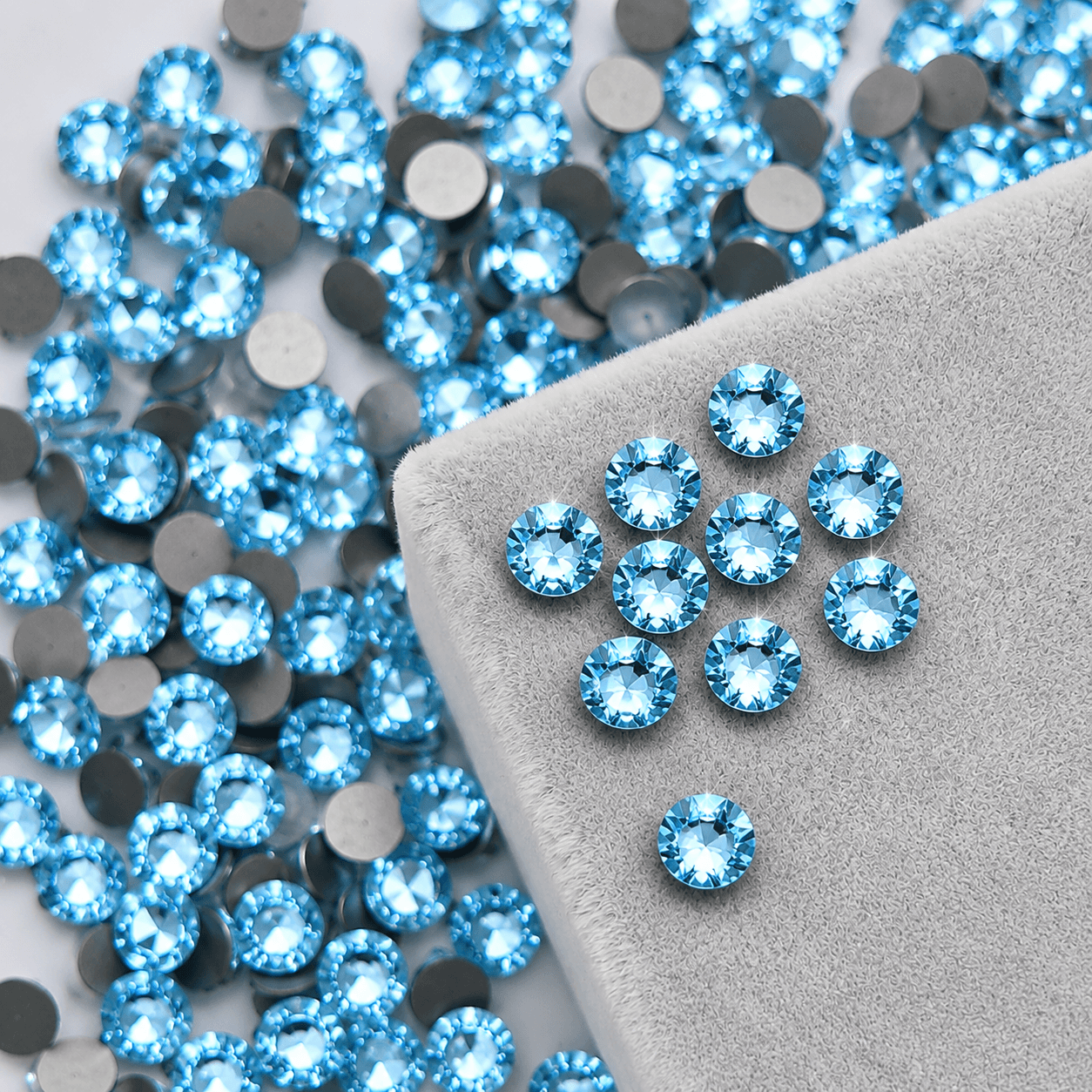 Blue high-shine round crystal tooth gems on gray velvet pad for professional tooth jewelry application by LaserGlow
