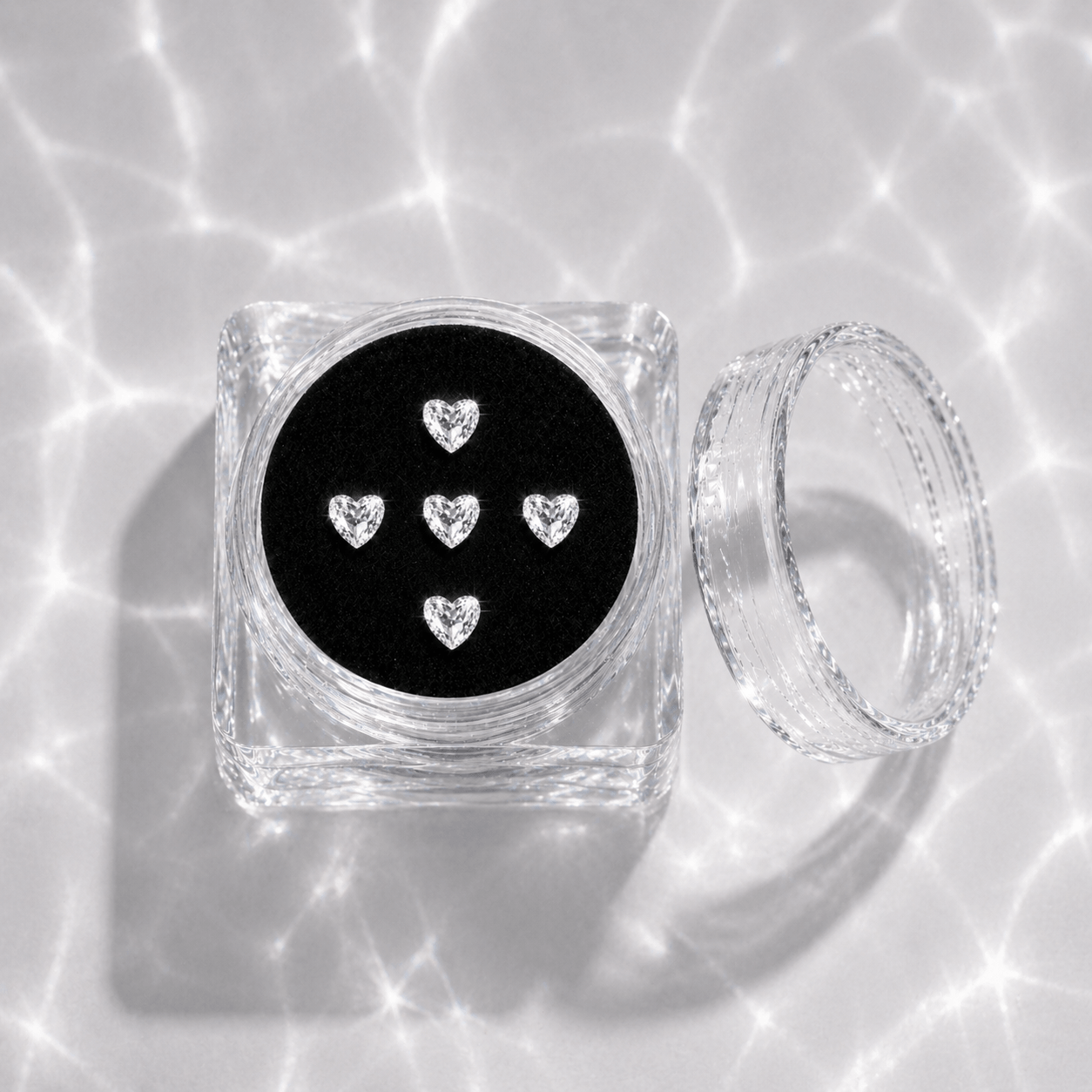 Five clear crystal heart tooth gems in a transparent acrylic display case