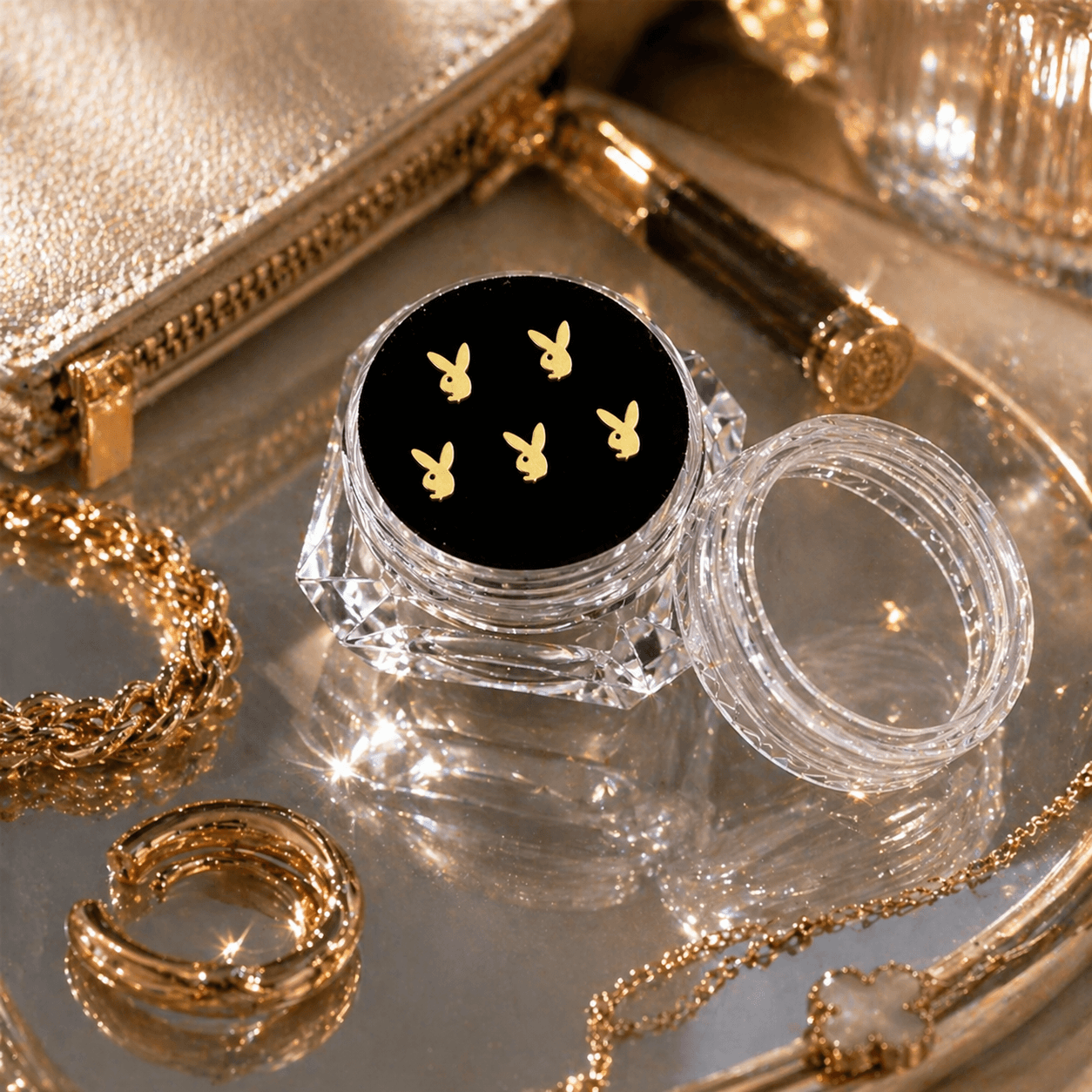 Gold bunny tooth gems 5-piece set displayed in a clear acrylic case on a luxury vanity tray with gold jewelry and reflective beauty accessories