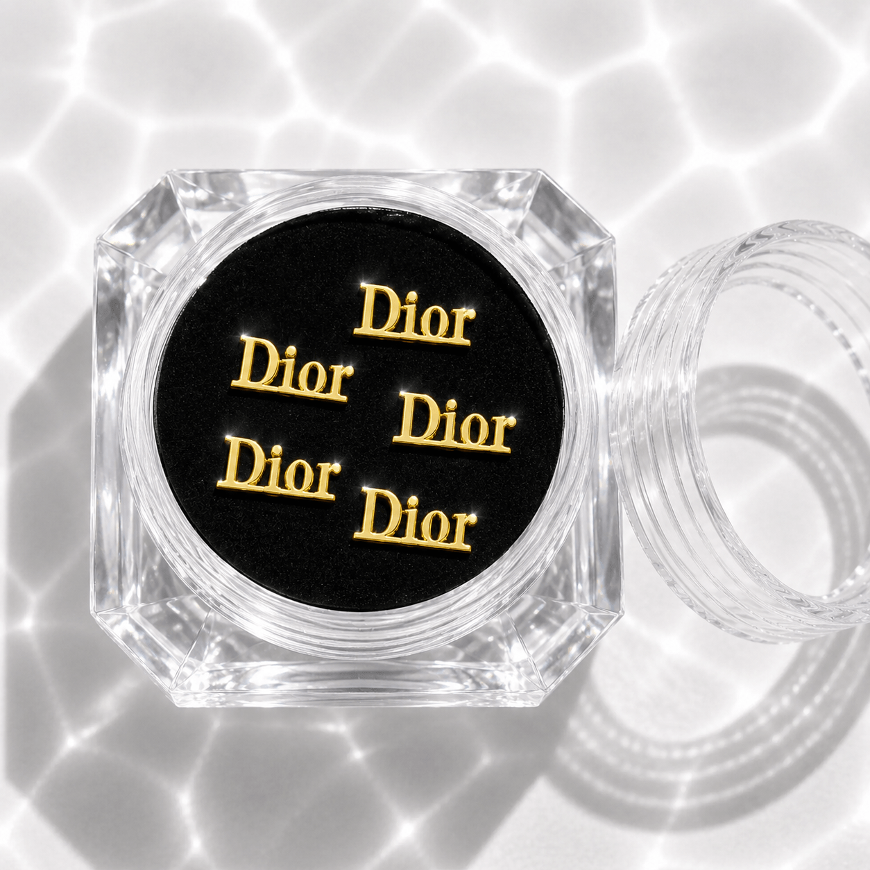 Five gold designer dior tooth gem charms in a clear acrylic display case