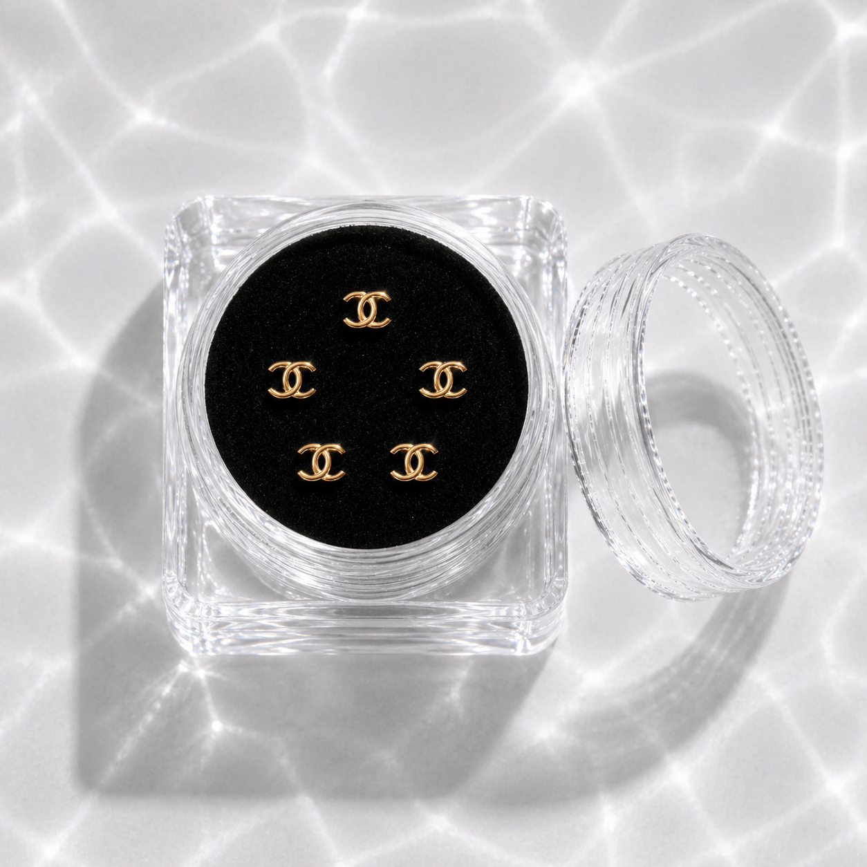 Five gold double-C tooth gem charms in a transparent acrylic display case