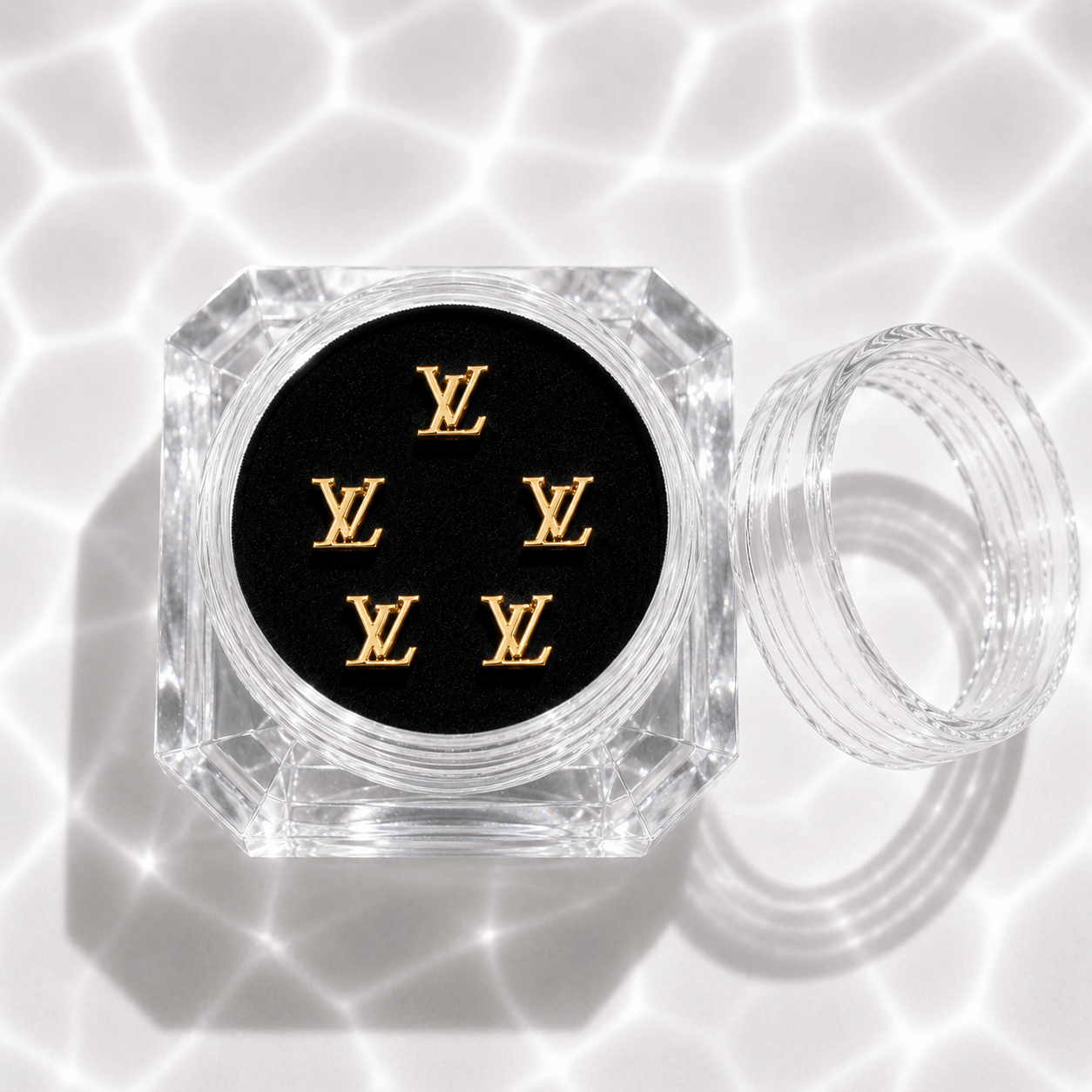 Five gold LV-style monogram tooth gem charms in a clear acrylic display case