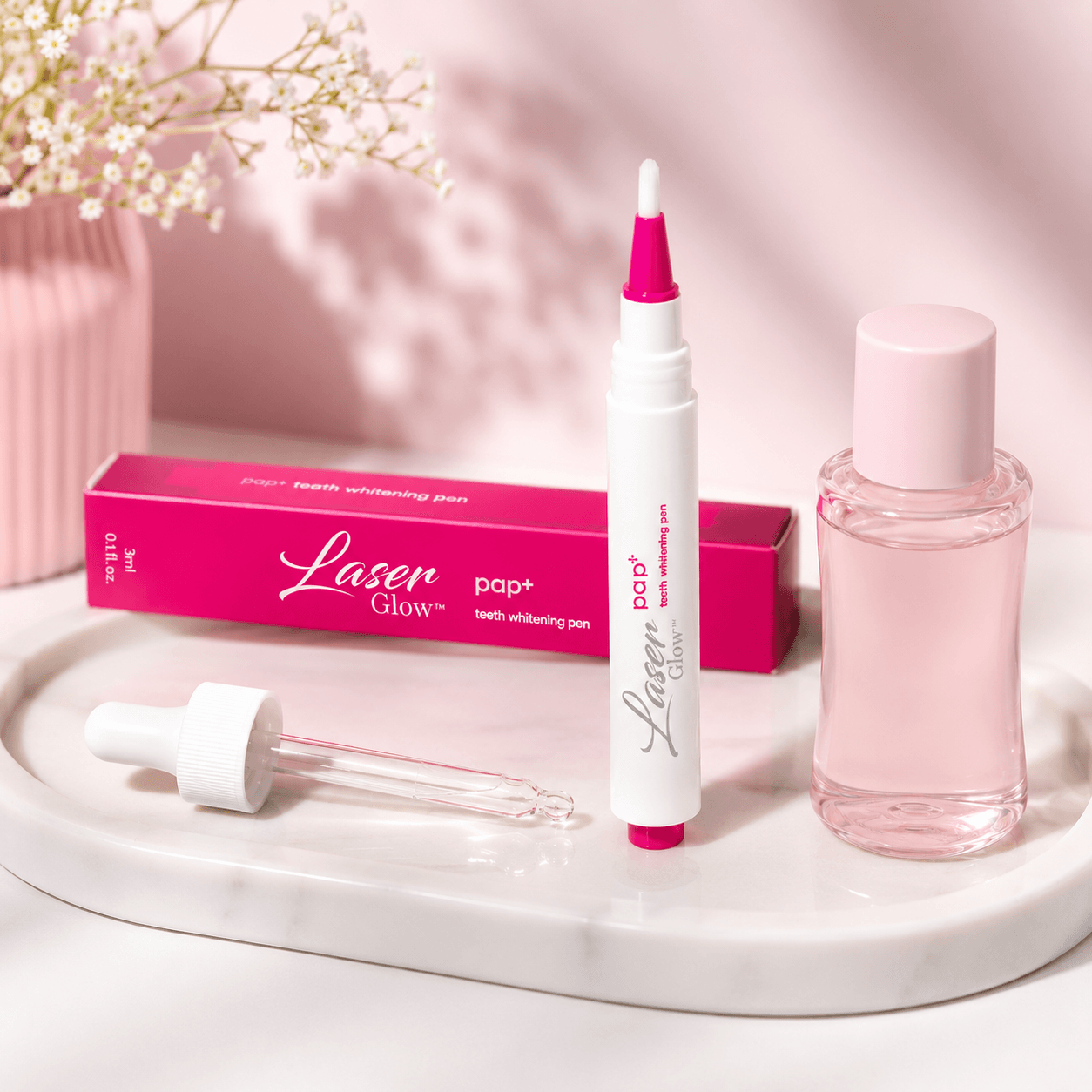 LaserGlow PAP teeth whitening pen lifestyle image with pink product box, brush applicator, peroxide-free whitening formula, and soft beauty vanity styling