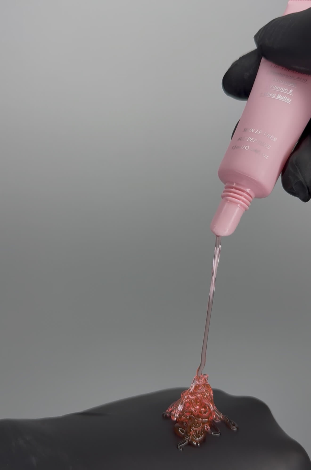 LaserGlow Polypeptide Lip Repair Oil dripping to reveal lightweight, glossy texture with HA5 Hyaluronic Acid, Arnica, Vitamin E, and Shea Butter
