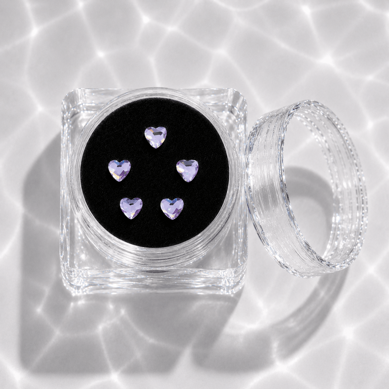 Five lavender purple crystal heart tooth gems in a clear acrylic display case