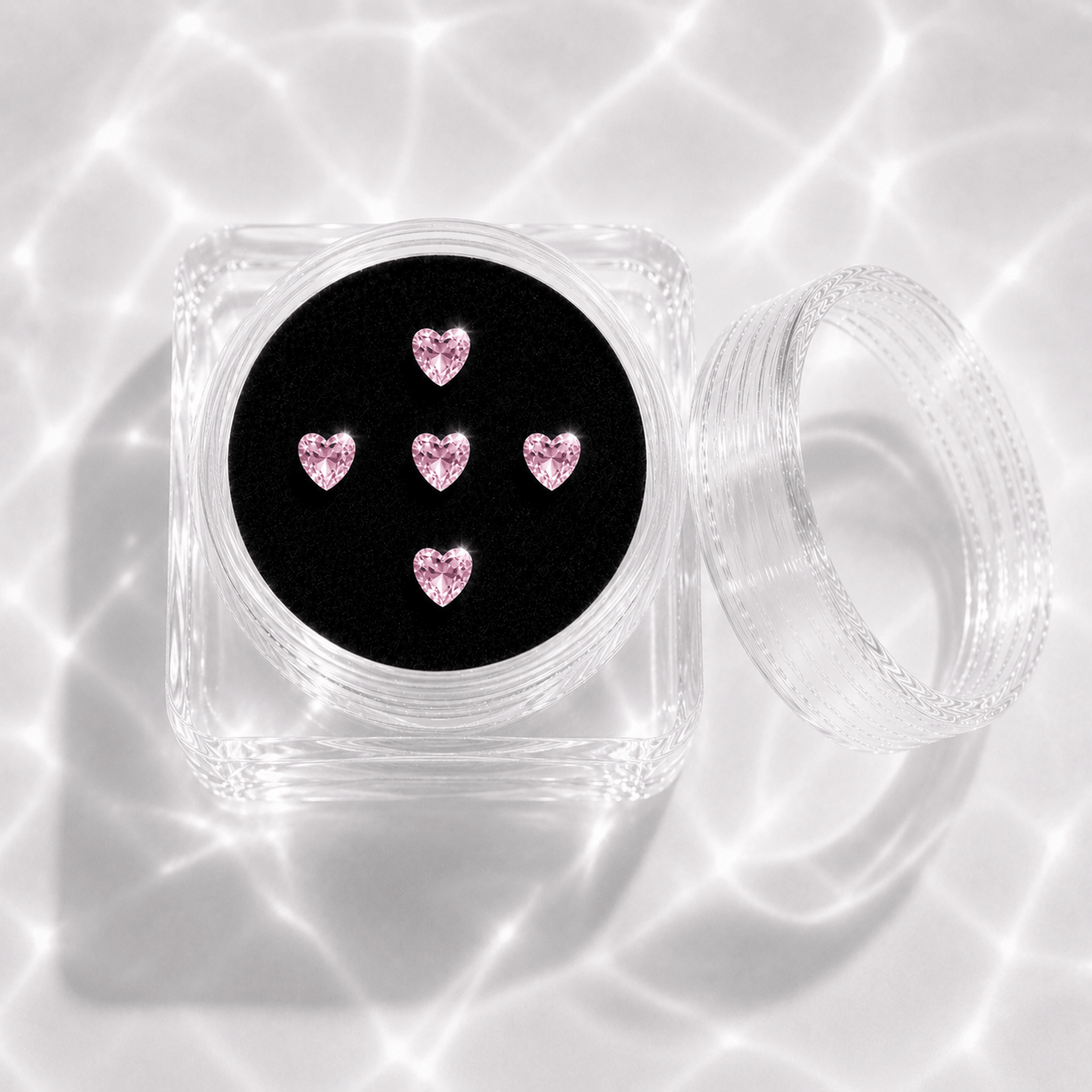 Five pink crystal heart tooth gems in a transparent acrylic display case