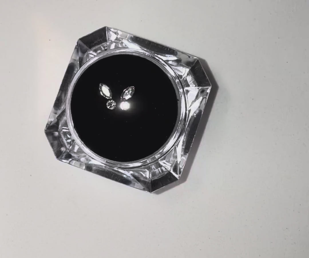 Load video: High-shine butterfly tooth gems by LaserGlow, reflecting studio lights in a close-up video.