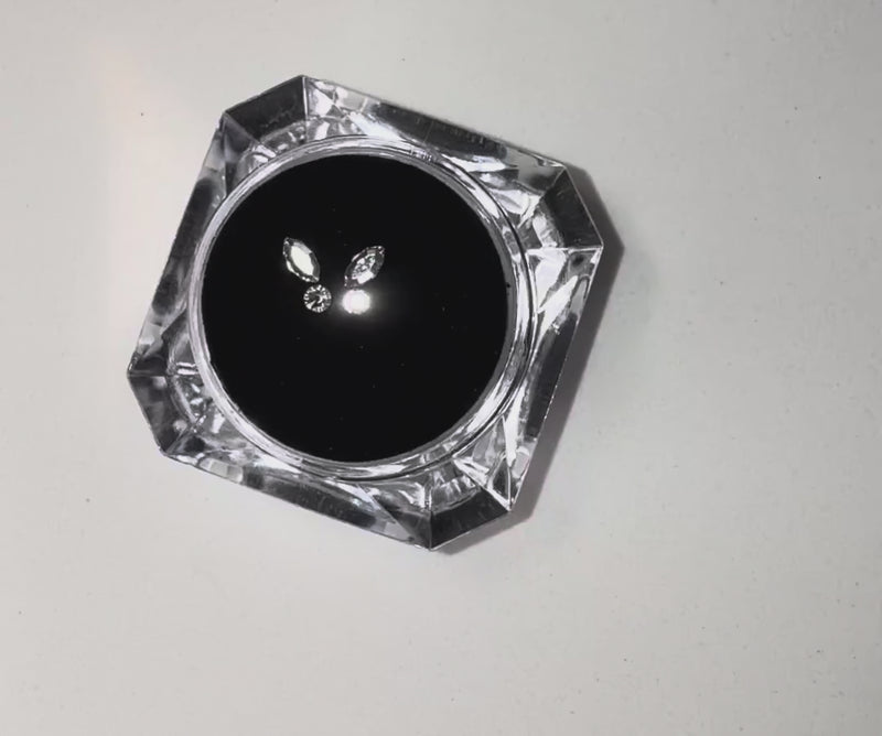 High-shine butterfly tooth gems by LaserGlow, reflecting studio lights in a close-up video.